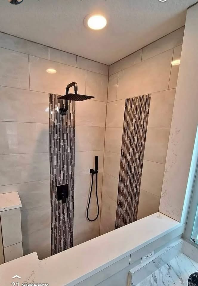 Large-format tile shower with vertical mosaic accent strips and matte black fixtures