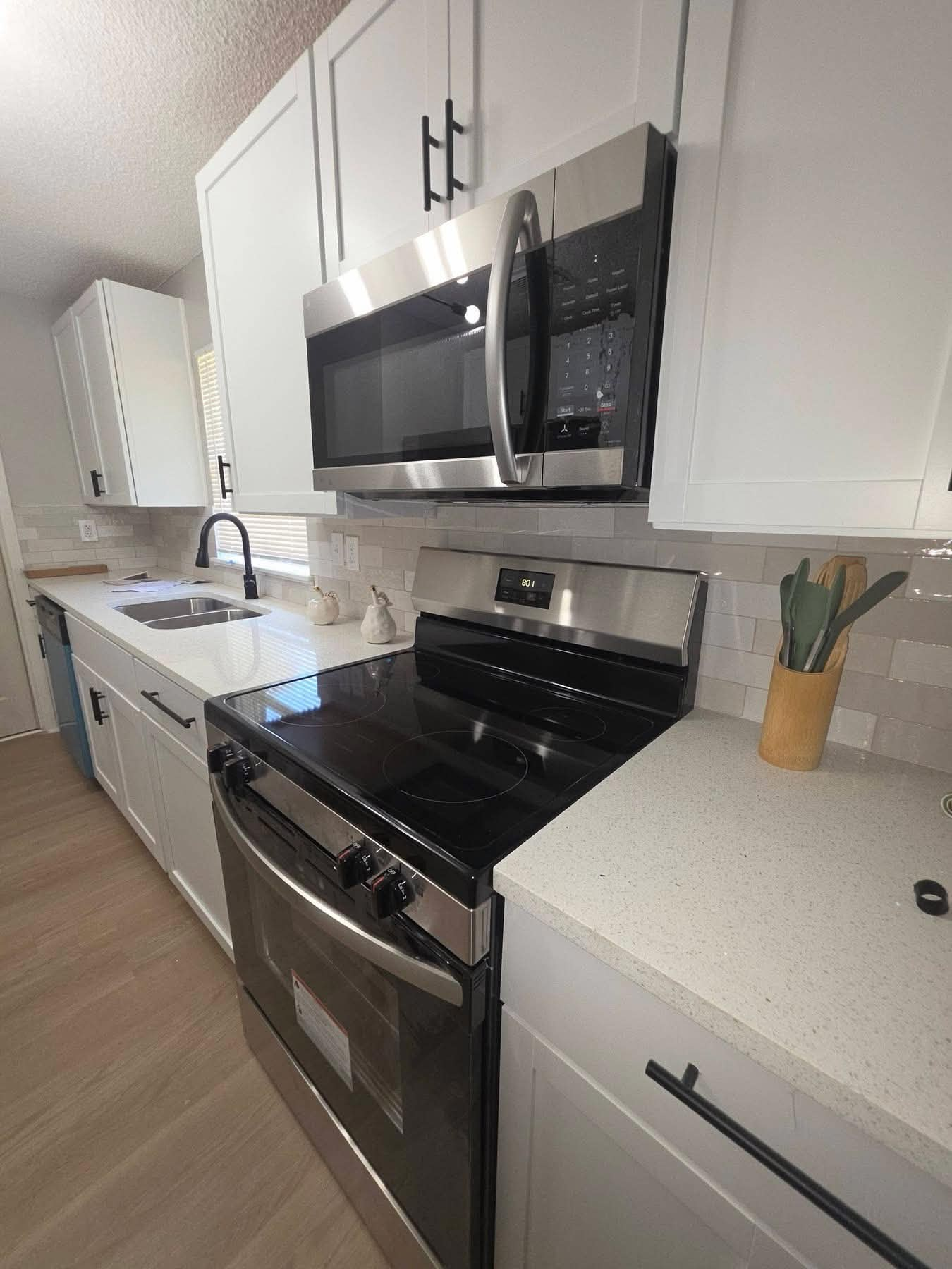 White shaker kitchen with quartz counters, subway backsplash and vinyl plank floor